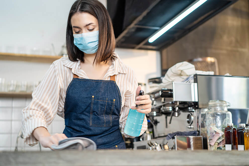 Woman cleaning and sanitizing countertop surfaces